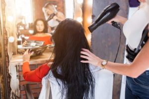 hairstylist blowdrying clients hair in chair