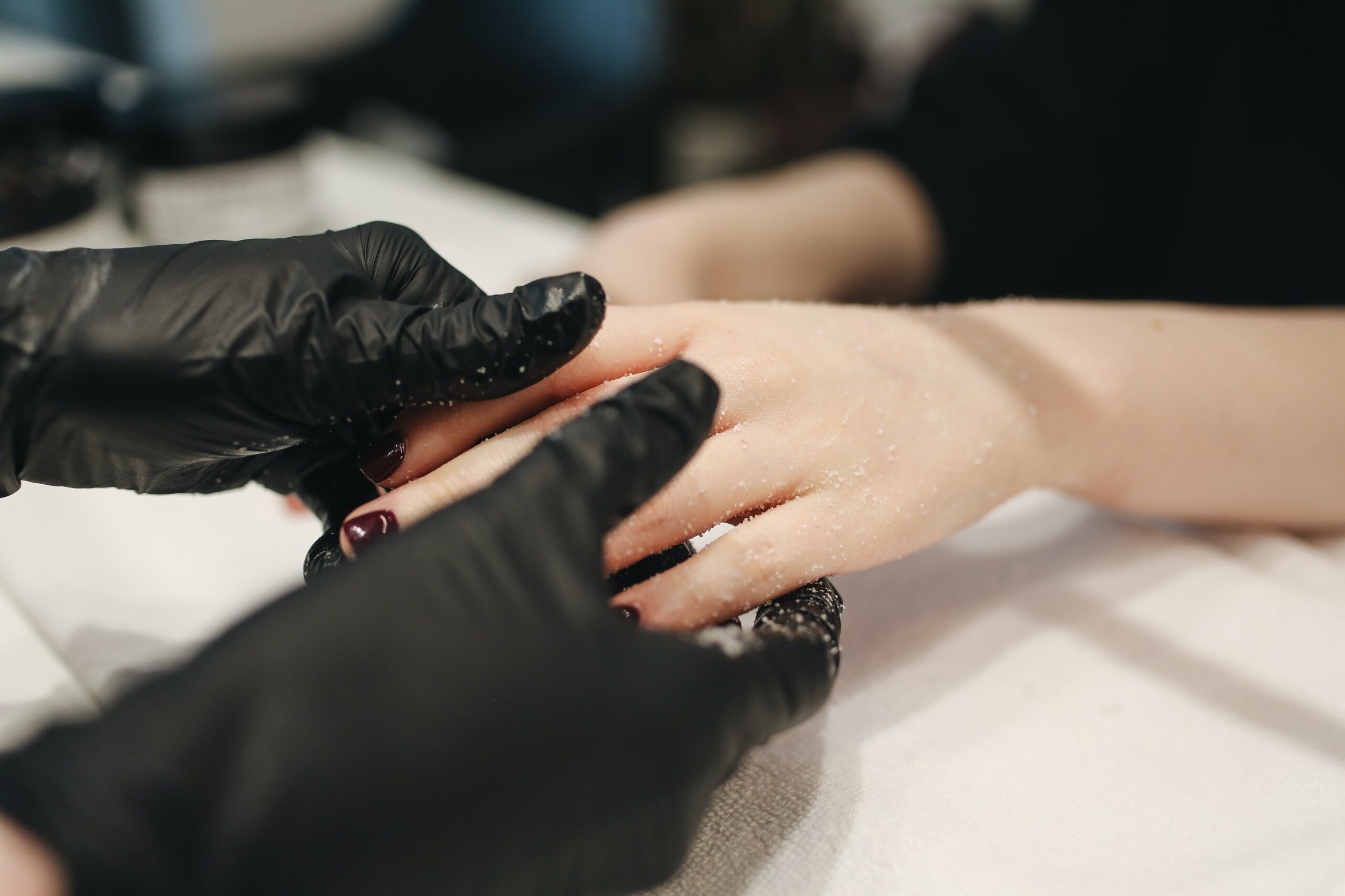 nail artists hands holding a womans hands to paint her nails