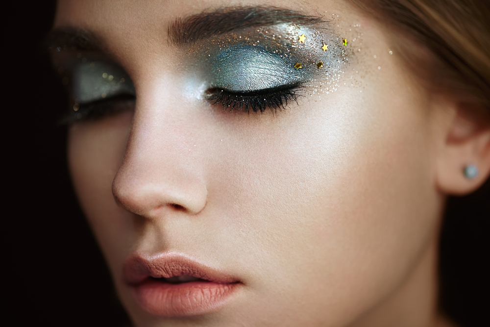 close up of slightly turned woman with blue and gold creative makeup