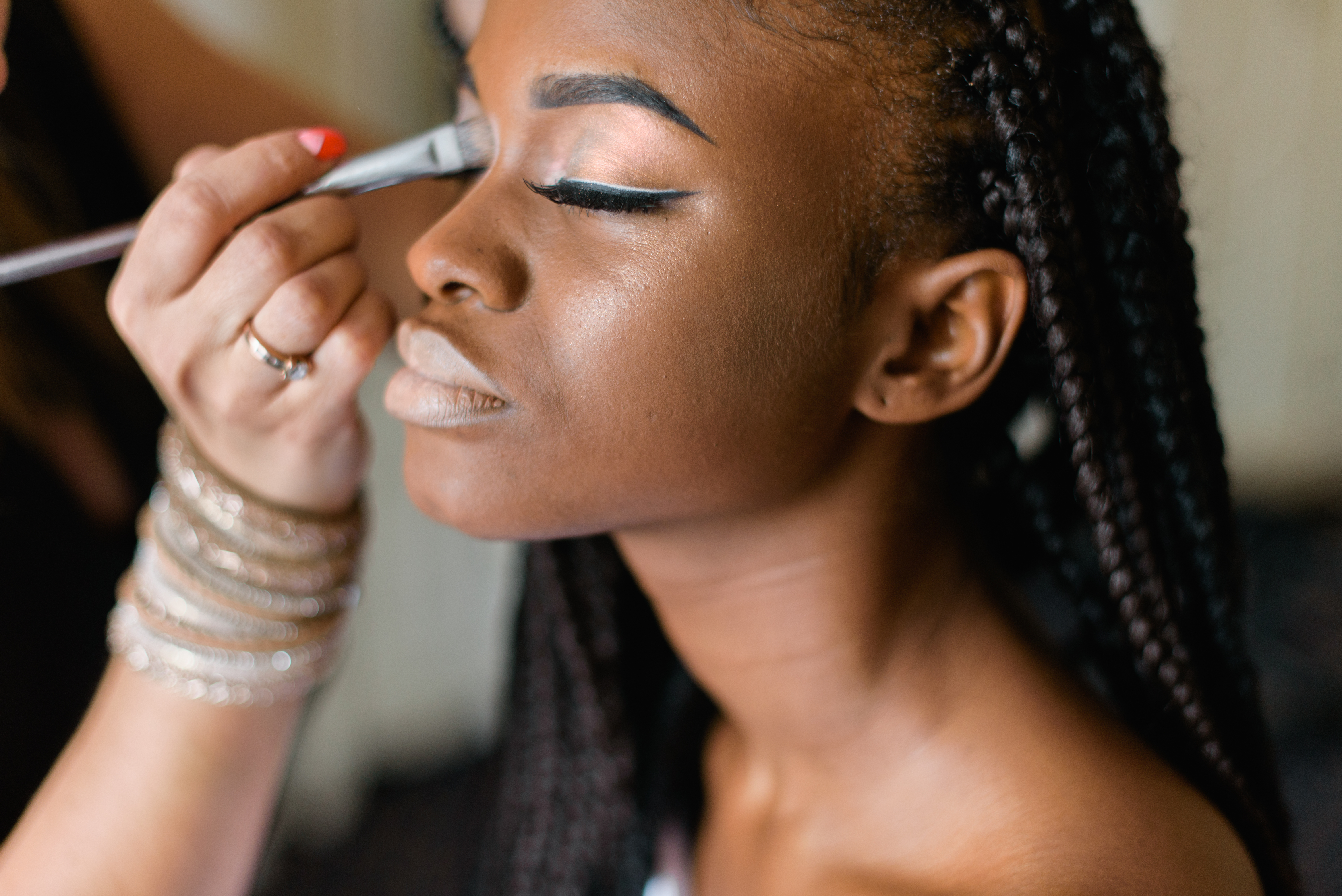 beautiful black woman with braids getting her makeup done