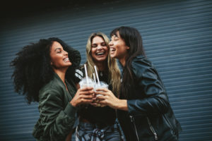 three ethnic girls laughing while cheering with fraps in their hands